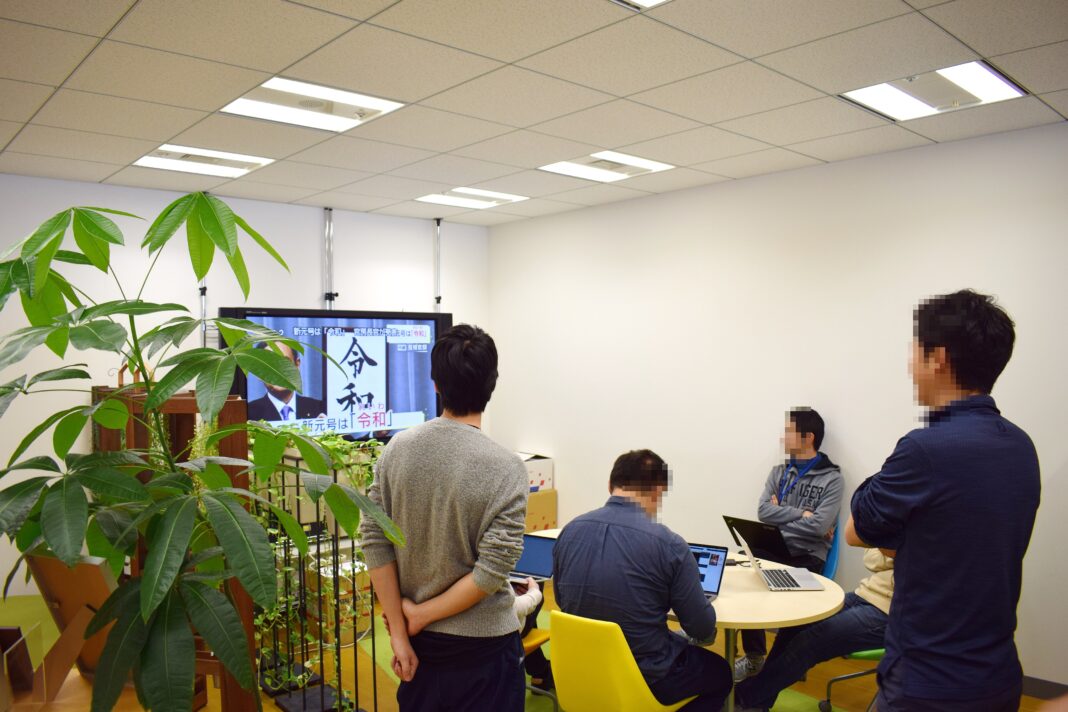 Does AI Adoption Tell Us More Than AI Exposure? What a 41-Country Study Shows Office workers in Japan gather around a television screen in a bright office