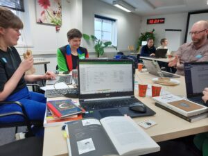 Hackathon participants work on laptops around tables in a meeting room