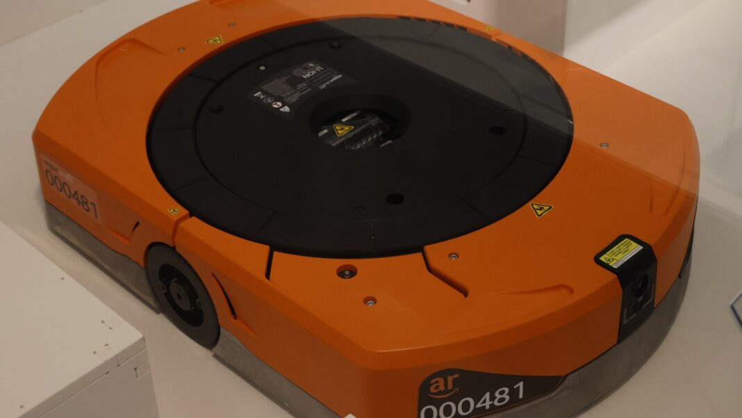 Amazon Plans a $100 Million-Plus Indiana Factory for Its Robotics Network, With 300 Skilled Jobs Close-up of an orange Amazon warehouse drive robot with a black circular lifting top
