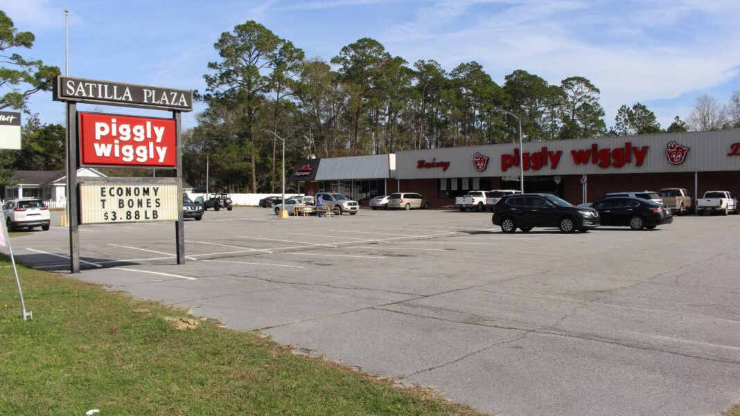 Georgia Piggly Wiggly Operator Will Pay $65,000 to Settle EEOC Religious-Accommodation Suit A Piggly Wiggly grocery store in a shopping-center parking lot, with a red Piggly Wiggly roadside sign in the foreground