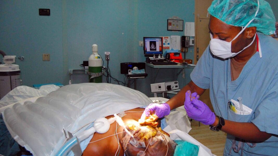 Healthcare Workforce Gap Could Nearly Double by 2040, Company-Backed Model Projects A nurse in blue scrubs, a surgical cap and a mask cleans a patient's skin before surgery in an operating room