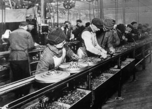 Workers stand along a moving assembly line at a Ford Motor Company plant in 1913