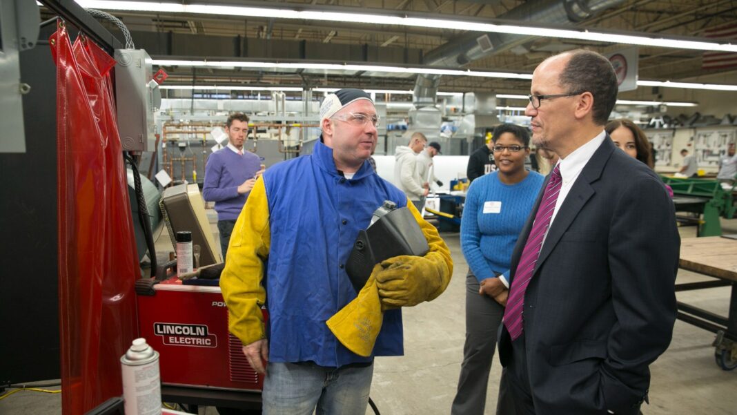 Sheet-Metal Apprentices Can Turn Training Into Up to 56 Rowan University Transfer Credits A sheet-metal apprentice in a blue welding jacket and yellow gloves talks with visitors in a large union training shop