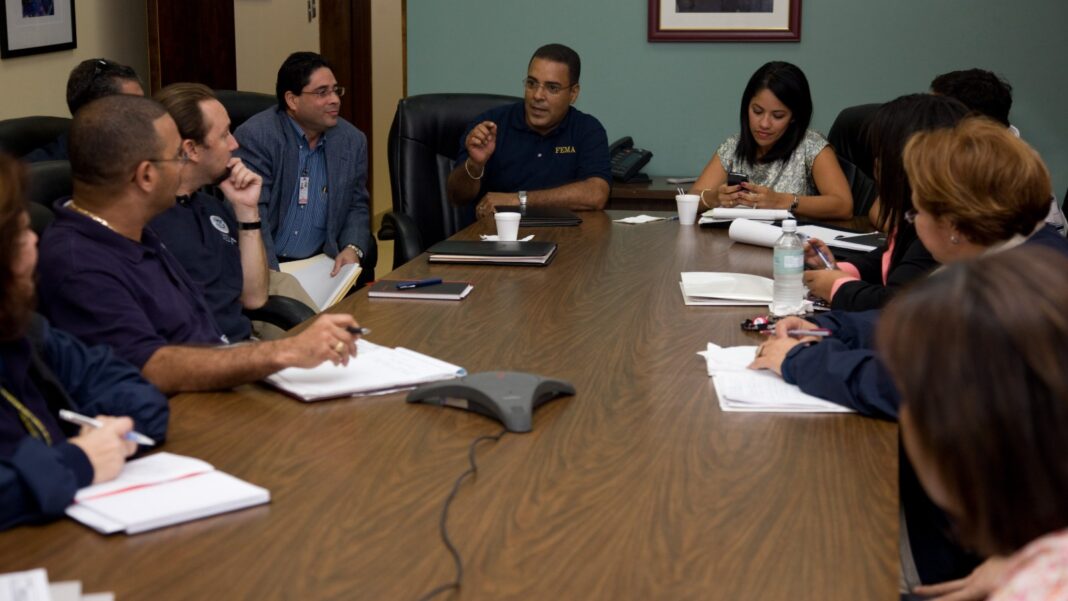 Workers Are Staying Longer With Employers, but the Hiring Signal Is More Complicated Office staff seated around a long conference table taking notes during a meeting