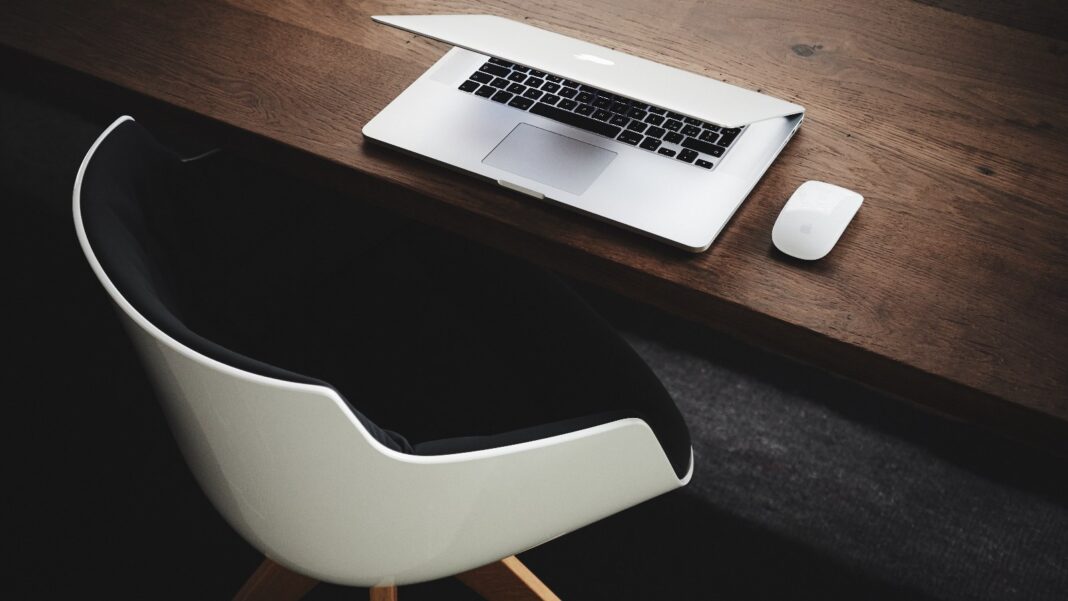 Airtable Cuts a ‘Large Portion’ of Its Staff Five Weeks After Bending Spoons Deal Closed A closed silver laptop and a wireless mouse on a dark wooden desk, with an empty white chair pulled up to it.