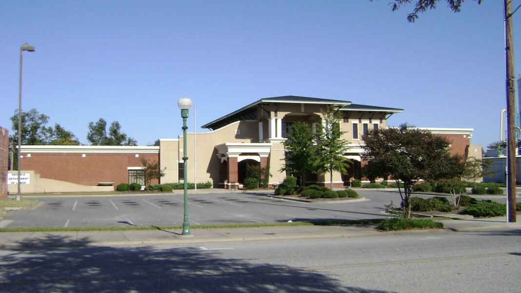 Georgia Lets Employers File Wage Reports With a Placeholder When a New Hire’s Social Security Number Is Missing A two-story brick and stucco office building with a tiled roof behind a parking lot, trees and a light pole under a blue sky