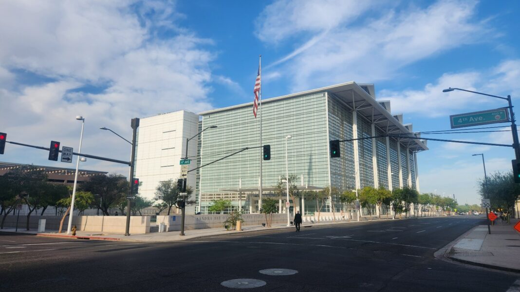 Federal Judge Tosses a 67-Page Workplace Complaint That Appeared AI-Generated and Bars AI in the Rewrite A tall glass-walled federal courthouse with an American flag on its roof, beside an empty city street