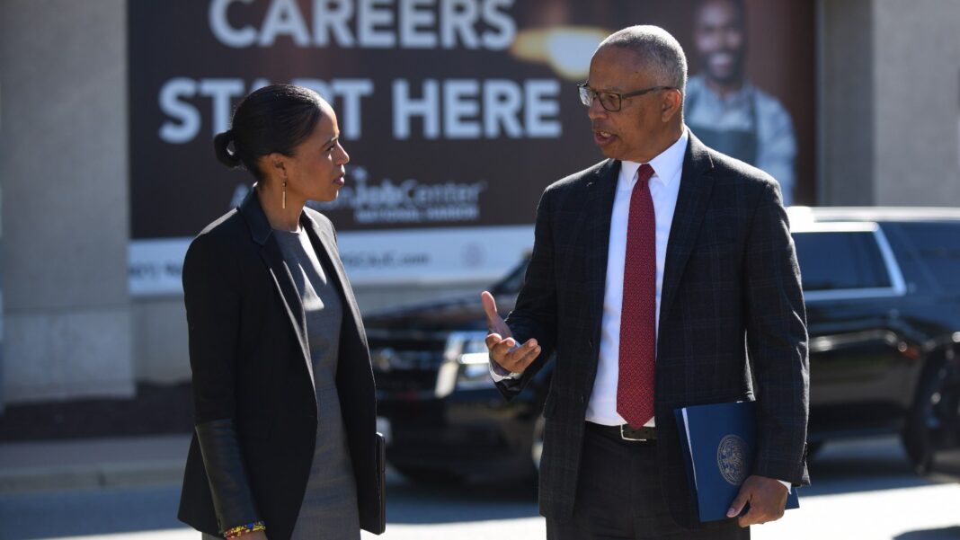 Long-Term Unemployment Still Accounts for More Than One in Four Unemployed Workers Two people in business attire talk outside a building with a large banner reading Careers Start Here