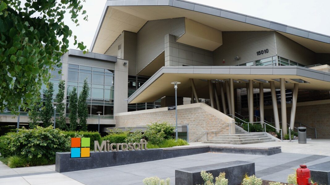 A modern building with an angular overhanging roof and a Microsoft logo sign in a landscaped plaza
