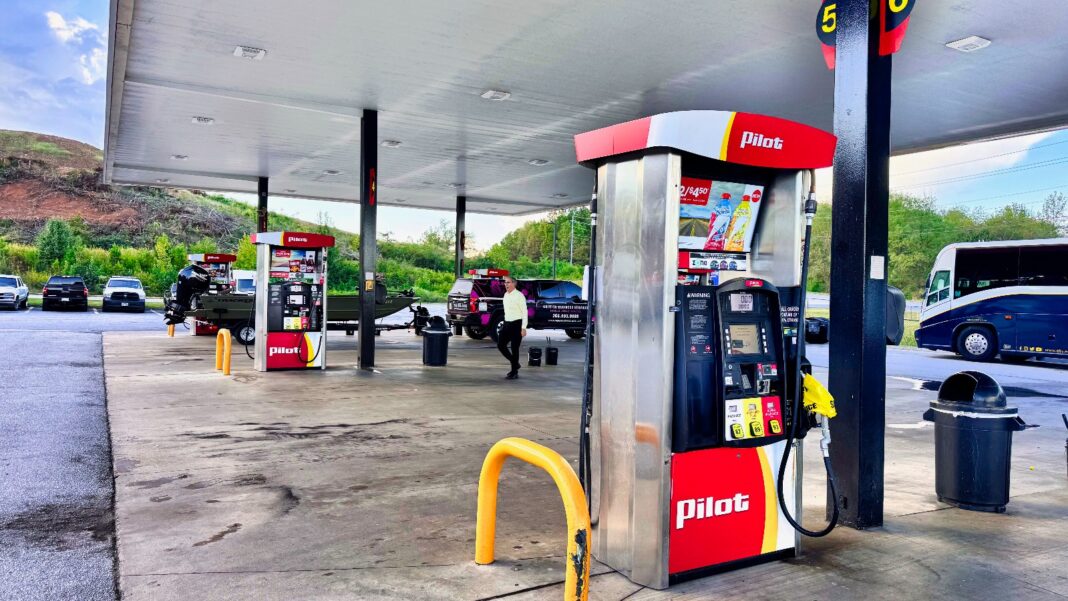 September Retail Sales Rise 0.8%, but Gasoline Accounts for Much of the Gain A red and white Pilot fuel pump under a gas station canopy, with more pumps, parked vehicles and green hills in the background.
